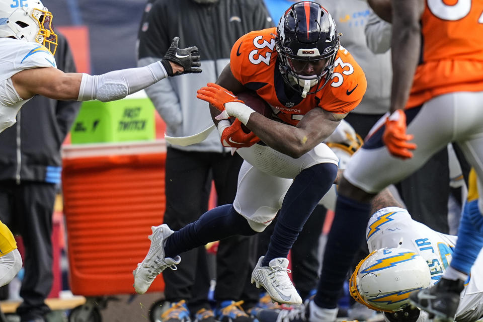 Denver Broncos running back Javonte Williams (33) gets by Los Angeles Chargers safety Alohi Gilman (32) during the first half of an NFL football game, Sunday, Dec. 31, 2023, in Denver. (AP Photo/Jack Dempsey)
