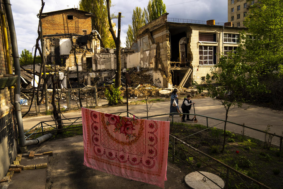 A tablecloth hangs to dry on a makeshift clothesline as residents walk past the Boychuk art academy, heavily damaged during a Russian bombing at the end of March, in Kyiv, Ukraine, April 23, 2024. (AP Photo/Francisco Seco)