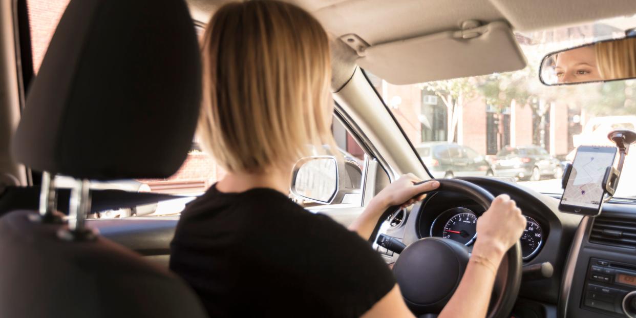 woman driving car with phone navigating