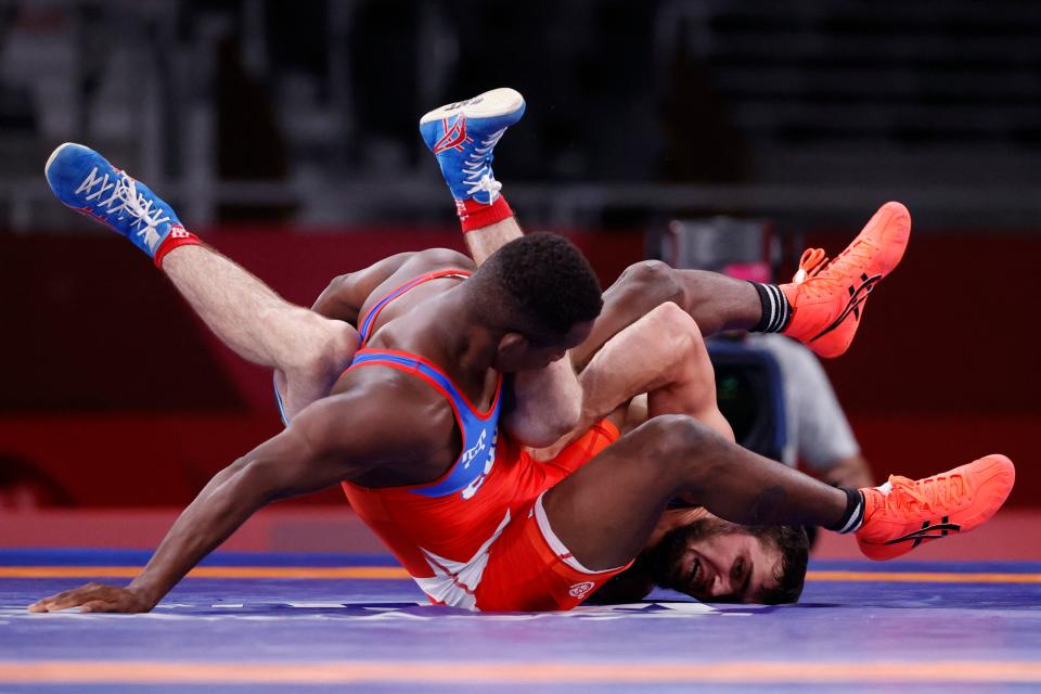 <p>Cuba's Jeandry Garzon Caballero (red) wrestles Belarus' Mahamedkhabib Kadzimahamedau in their men's freestyle 74kg wrestling early round match during the Tokyo 2020 Olympic Games at the Makuhari Messe in Tokyo on August 5, 2021. (Photo by Jack GUEZ / AFP)</p> 