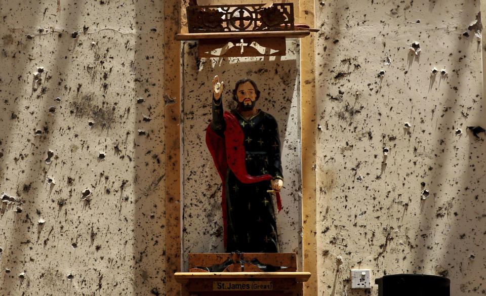 In this Thursday, April 25, 2019 photo, a statue of St. James stands on a wall speckled with fragments of shrapnel at St. Sebastian's Church, where a suicide bomber blew himself up in Negombo, north of Colombo, Sri Lanka. Nearly a week later, the smell of death is everywhere, though the bodies are long gone. Yet somehow, there’s a beauty to St. Sebastian’s, a neighborhood church in a Catholic enclave north of Sri Lanka’s capital. You can see the beauty in the broken stained-glass windows. It’s there as the sun shines through the roof’s gaping holes. It’s there in the little statues that refused to fall over, and despite the swarms of police and soldiers who seem to be everywhere now in the streets of the seaside town of Negombo. (AP Photo/Manish Swarup)