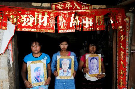 Women pose while holding portraits of their killed relatives (L-R) Aik Sai, Aik Maung and Aik Lort after their bodies were found in a grave last June at Mong Yaw village in Lashio, Myanmar July 10, 2016. REUTERS/Soe Zeya Tun