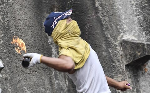 n anti-government demonstrator throws a Molotov cocktail during clashes with police and troops in the surroundings of a National Guard command post in Cotiza - Credit: YURI CORTEZ/&nbsp;AFP