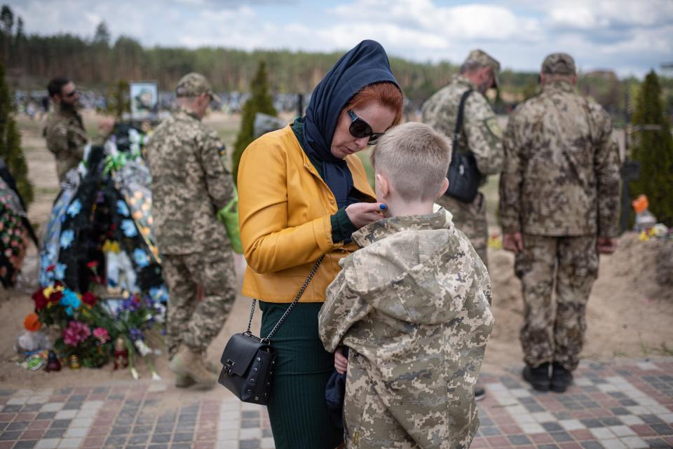 A woman hugs her son as Ukrainian soldiers pay respects to their fallen comrades on May 1, 2022, in Irpin, Ukraine.