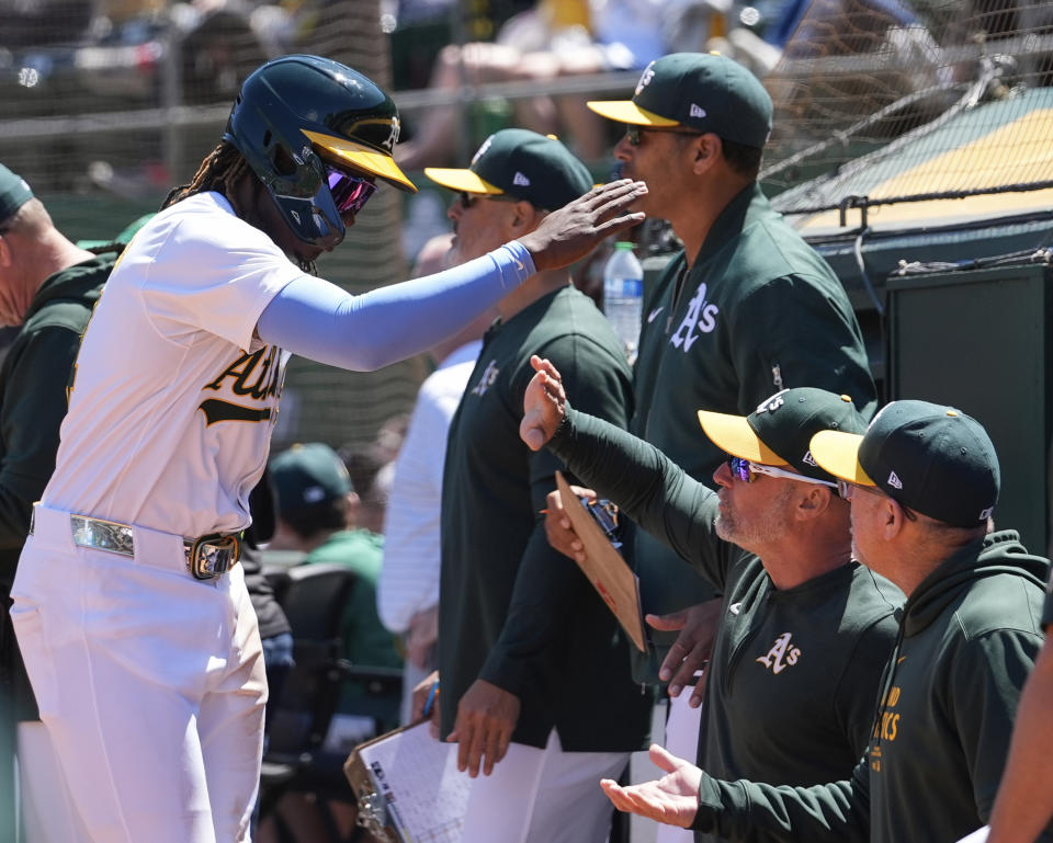 Oakland Athletics' Lawrence Butler, left, celebrates with manager Mark Kotsay, second from right, at the dugout after scoring against the Miami Marlins during the fourth inning of a baseball game Sunday, May 5, 2024, in Oakland, Calif. (AP Photo/Godofredo A. Vásquez)