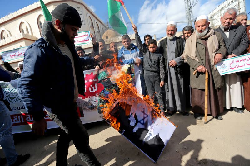 FILE PHOTO: A Palestinian demonstrator burns a picture depicting U.S. President Donald Trump and Israeli Prime Minister Benjamin Netanyahu, during a protest against Trump's Middle East peace plan, in the southern Gaza Strip