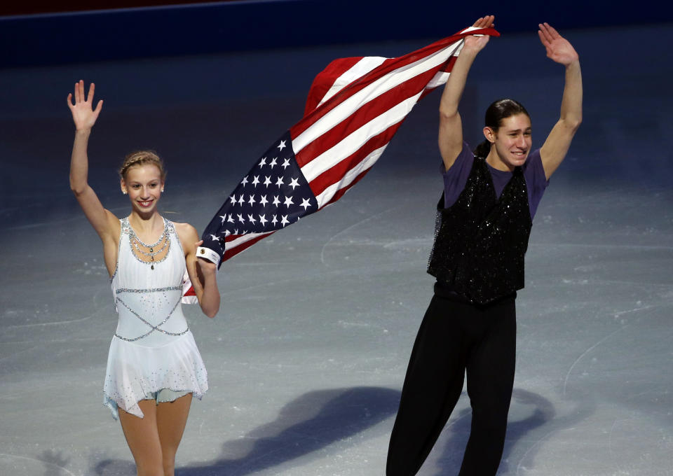 U.S. Olympic figure skaters Polina Edmunds and Jason Brown carry a flag and wave to the crowd at the end of their skating spectacular after the U.S. Figure Skating Championships in Boston, Sunday, Jan. 12, 2014. (AP Photo/Elise Amendola)