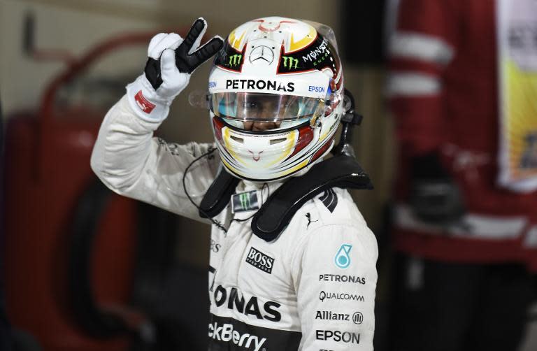 Mercedes AMG Petronas British driver Lewis Hamilton flashes the sign for victory after winning pole position for the Formula One Bahrain Grand Prix following the qualification session at the Sakhir circuit on April 18, 2015