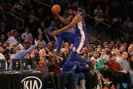 Feb 13, 2019; New York, NY, USA; Philadelphia 76ers center Joel Embiid (21) saves a ball from going out of bounds by jumping into the stands over Actress Regina King (brown sweater) during the third quarter against the New York Knicks at Madison Square Garden. Brad Penner-USA TODAY Sports