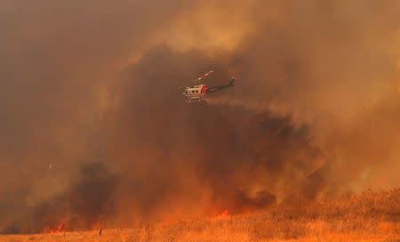 FILE PHOTO: A helicopter drops water on a wind driven wildfire in Orange, California, U.S., October 9, 2017. REUTERS/Mike Blake/File Photo