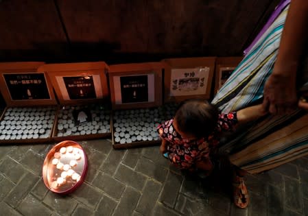 A child looks at candles on the ground as people gather at Lennon Wall at Admiralty district during the Mid-Autumn Festival, in Hong Kong