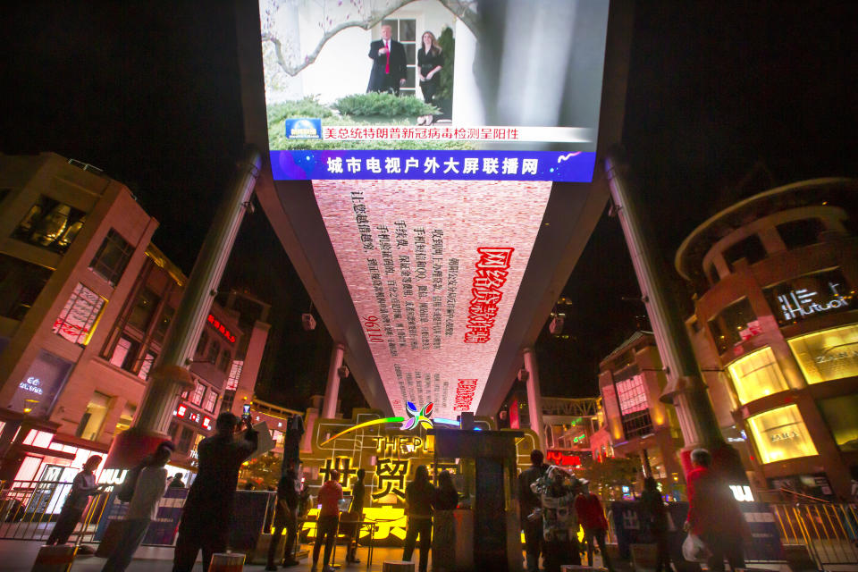 FILE - In this Oct. 2, 2020, file photo, people watch a large screen showing President Donald Trump and First Lady Melania Trump during a news report from Chinese state television about Trump testing positive for the coronavirus in Beijing. Chinese leaders hope Washington will tone down conflicts over trade, technology and security if Joe Biden wins the Nov. 3 presidential election. But any shift is likely to be in style, not substance, as frustration with Beijing increases across the American political spectrum. (AP Photo/Mark Schiefelbein, File)