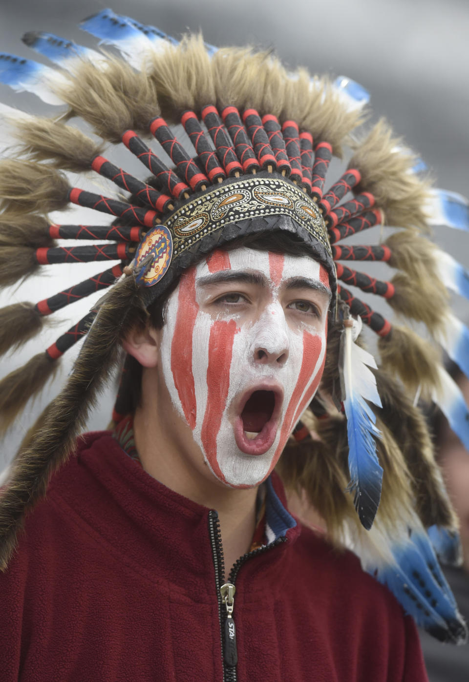 FILE - In this May 20, 2015, file photo, a Cheyenne Mountain High School student wears a headdress and face paint as he cheers for his school -- which uses "Indians" as its team mascot -- in the 4A State Soccer Championship game at Dick's Sporting Goods Park in Commerce City, Colo. The U.S. has spent most of 2019 coming to grips with blackface and racist imagery, including a racist photo on the Virginia governor’s college yearbook page. But Native Americans say they don't see significant pressure applied to those who perpetuate Native American stereotypes. (Mark Reis/The Gazette via AP, File)