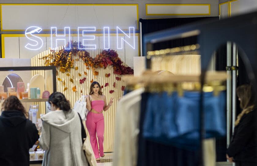 Ontario, CA - October 19: Shoppers Ashley Sanchez, center, of Fontana, poses for her friend Joscelin Flores, not pictured, who was taking photos with their bags of merchandise after being among the first group of shoppers taking the opportunity to shop on the opening day of fast fashion e-commerce giant Shein, which is hosting a brick-and-mortar pop up inside Forever 21 at the Ontario Mills Mall in Ontario Thursday, Oct. 19, 2023. (Allen J. Schaben / Los Angeles Times)