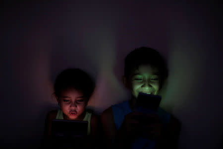 FILE PHOTO: Children use mobile phones during a blackout in Maracaibo, Venezuela April 12, 2019. REUTERS/Ueslei Marcelino