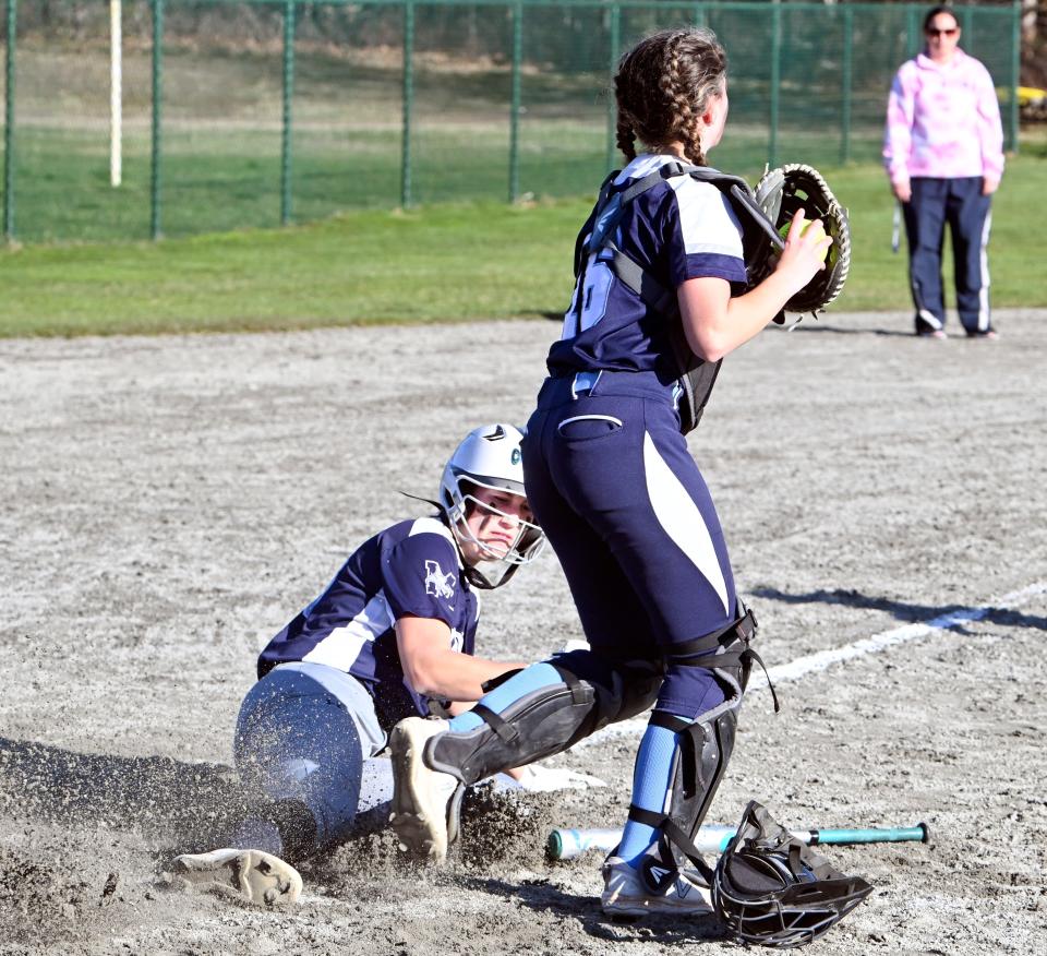 Courtney Kelley of Monomoy slides into home after being forced by Sandwich catcher Cece Donovan.