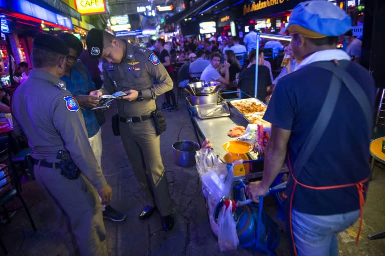 Police inspect passports in Bangkok's Patpong district during an "X-Ray Outlaw Foreigner" operation
