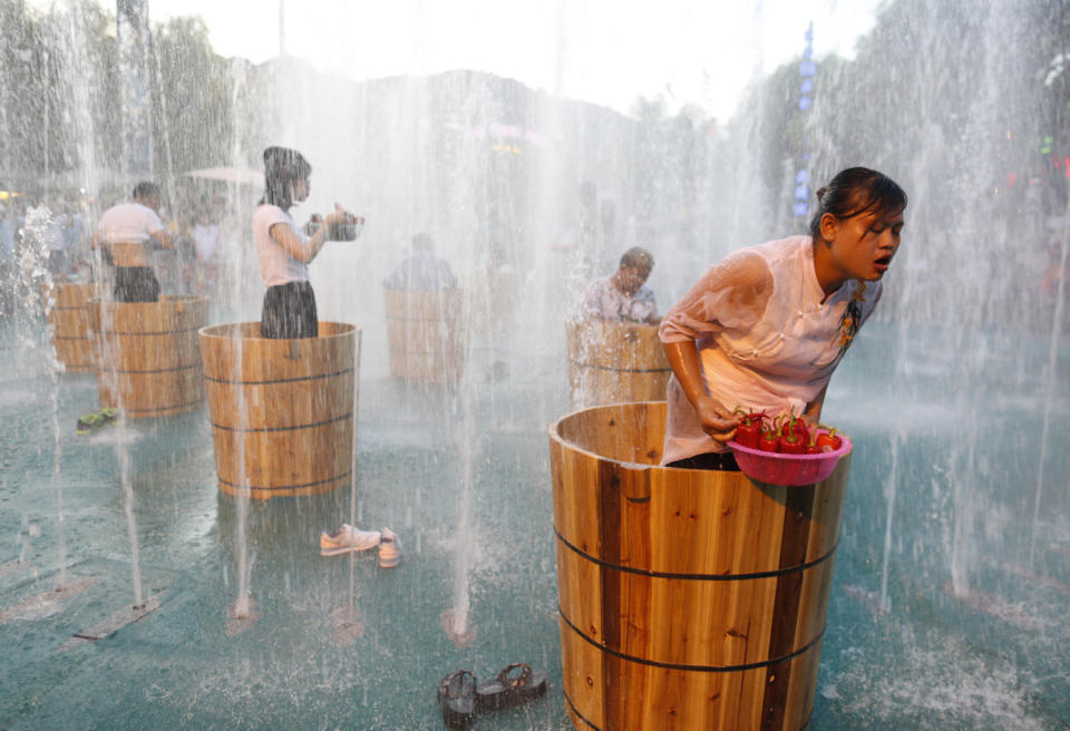 Tourists standing in the ice buckets eat peppers in the fountain during a competition at Song Dynasty Town on July 20, 2016 in Hangzhou, Zhejiang Province of China.