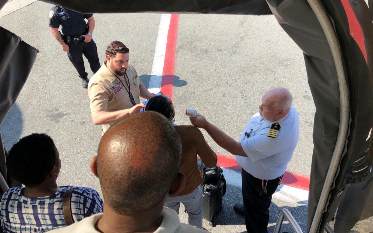 A passenger gets her temperature taken as she leaves an Emirates airplane at New York's Kennedy Airport amid reports of ill passengers aboard a flight from Dubai - Larry Coben