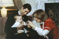 ARCHIVO - En esta fotografía del 22 de diciembre de 1982, el príncipe Guillermo, el hijo de seis meses de edad del príncipe Carlos y la princesa Diana, interactúa con sus padres durante una sesión fotográfica en el Palacio de Kensington, en Londres. (AP Foto/David Caulkin, Archivo)