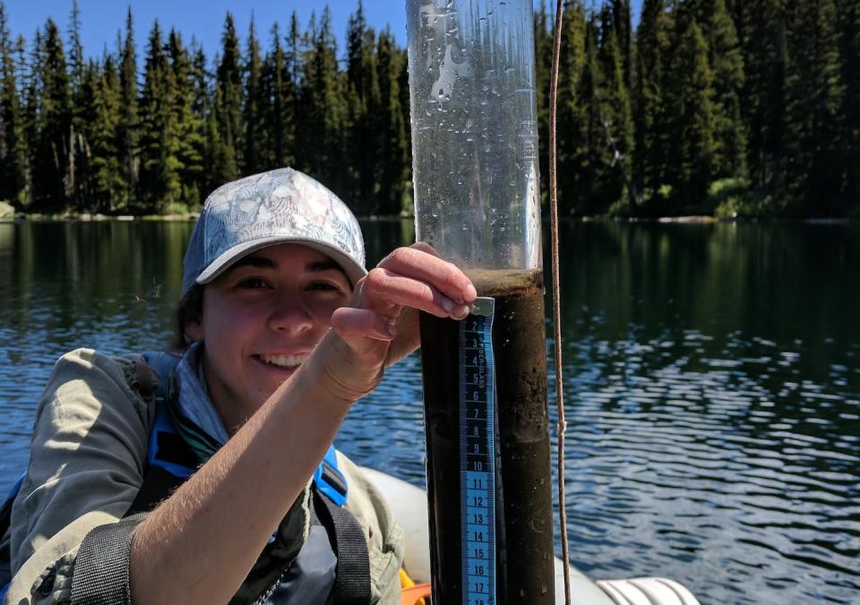 Author Kyra Clark-Wolf holds a sediment core pulled from a lake containing evidence of fires over thousands of years. Philip Higuera