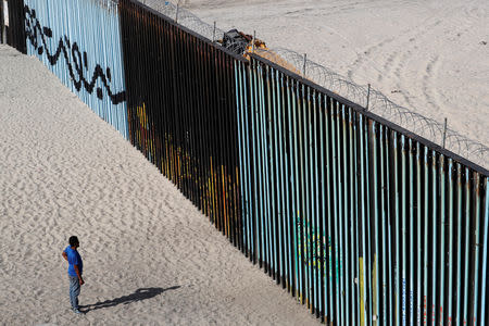 A migrant, part of a caravan of thousands trying to reach the U.S., looks at the border fence between Mexico and the United States, in Tijuana, Mexico November 15, 2018. REUTERS/Carlos Garcia Rawlins