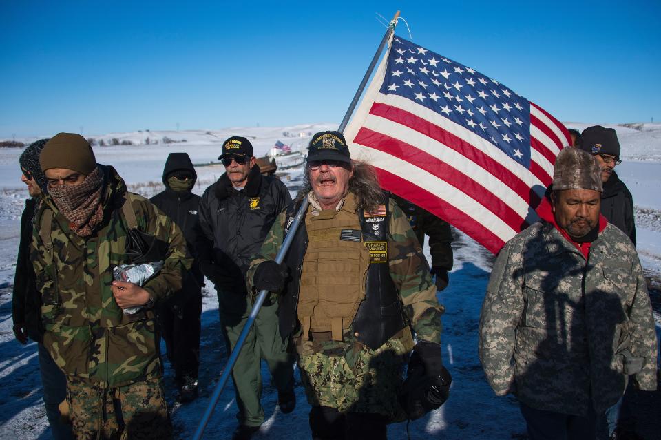 U.S. Navy deep sea diving veteran Rob McHaney (C) holds an American flag as he leads a group of veteran activists back from a police barricade on a bridge near Oceti Sakowin Camp on the edge of the Standing Rock Sioux Reservation.