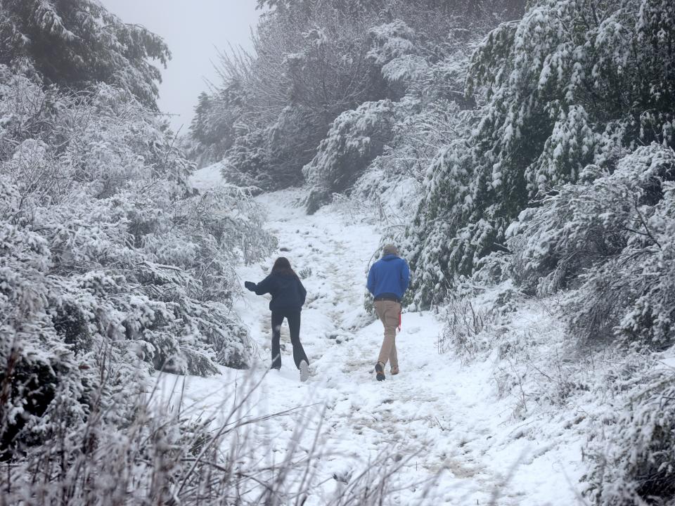 Two people walking up a snowy trail in Berkeley, California.