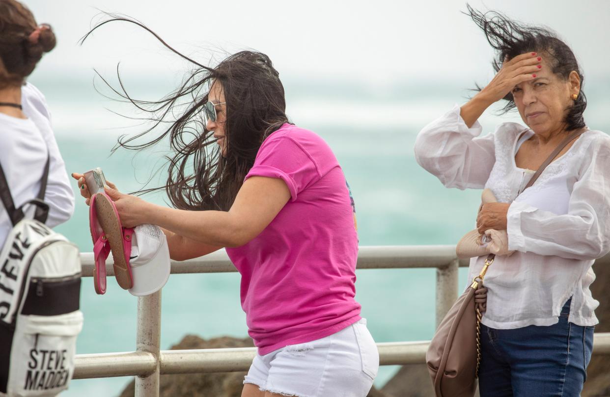 Tourists Bianca Garcia, left, and Rafaela Delgadillo experience the windy weather as they walk on the ocean inlet jetty in Jupiter, Florida on January 9, 2024.
