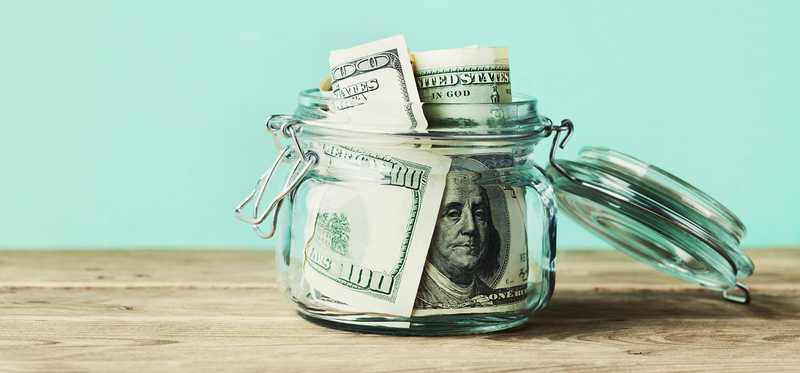 Hundred dollar bills stored in a glass jar.