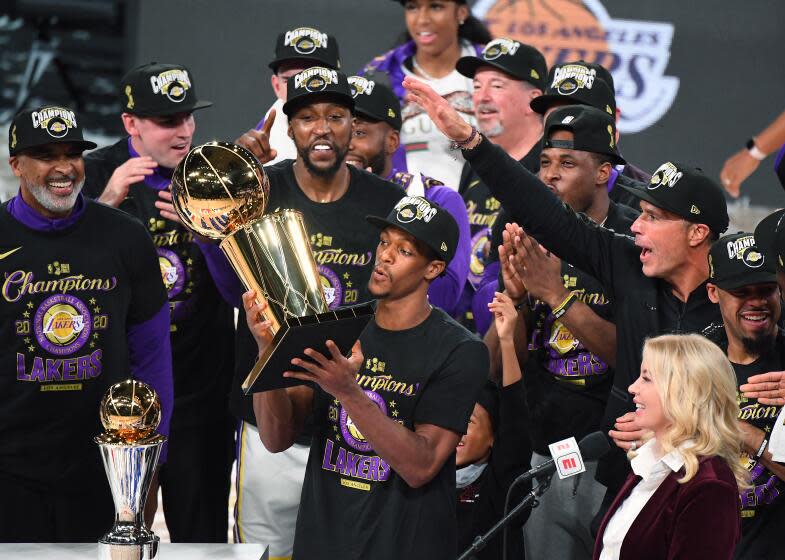 Rajon Rondo is surrounded by his teammates as he holds the trophy after the Lakers won the 2020 NBA championship.