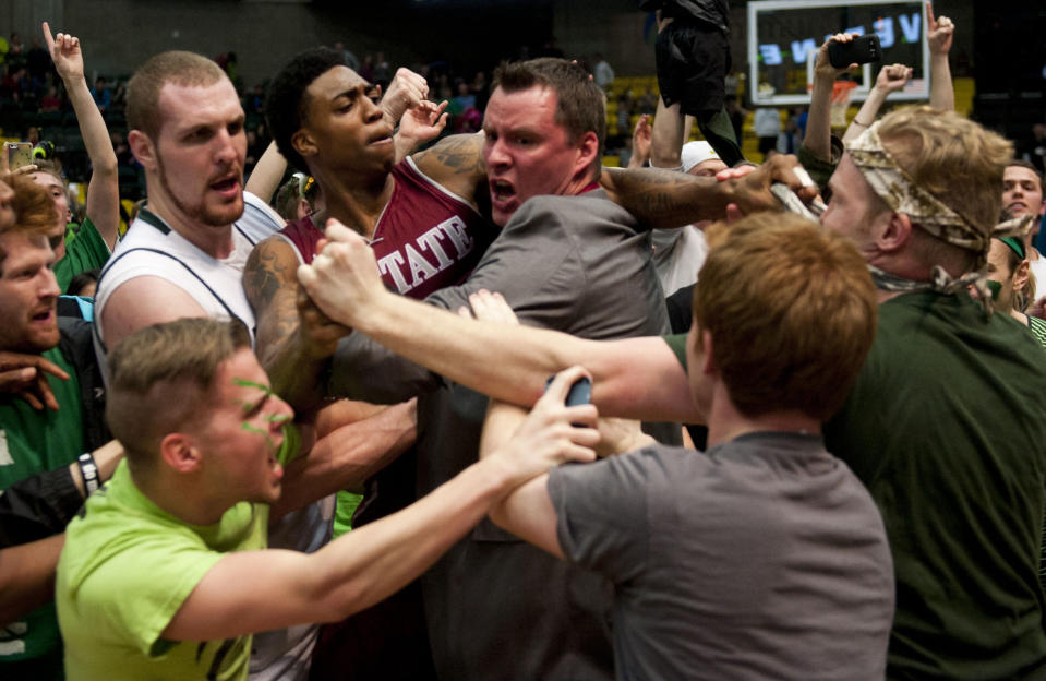 In this Thursday, Feb. 27, 2014 photo, New Mexico State's Daniel Mullings, center left in red and white jersey, is involved in a brawl involving players and fans who came onto the court when New Mexico State guard K.C. Ross-Miller hurled the ball at Utah Valley's Holton Hunsaker seconds after the Wolverines' 66-61 overtime victory against the Aggies in Orem, Utah. (AP Photo/The Daily Herald, Grant Hindsley) MANDATORY CREDIT