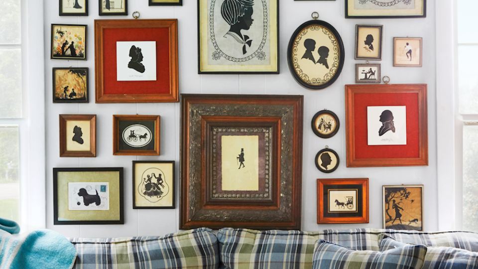 a collection of silhouettes hangs behind a plaid sofa in a living room