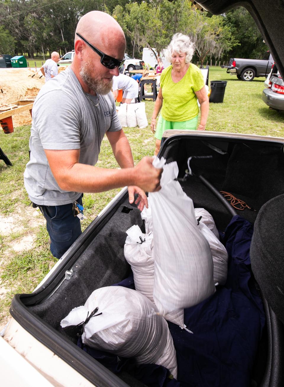 City of Ocala employee and irrigation specialist James Carsey helps Anna Wolff load sand bags into the trunk of her car Wednesday afternoon at Jervey Gantt Park in Ocala.