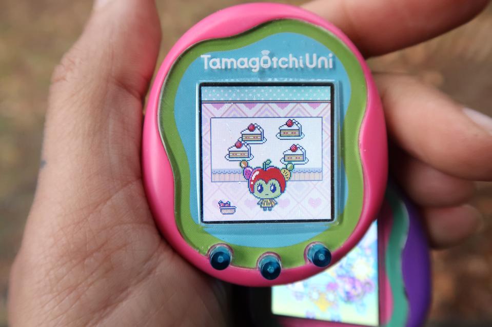 Pink Tamagotchi Uni retratado em uma mão exibindo o novo personagem Tanghulutchi