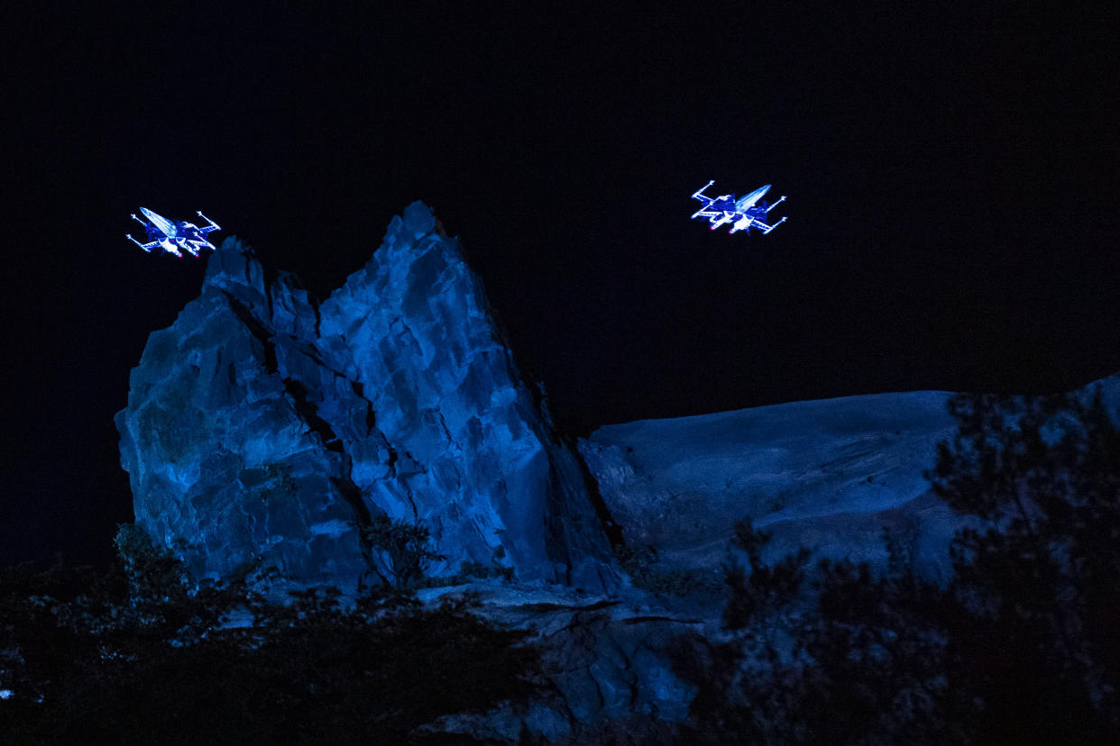  Two illuminated spaceships rise above a mock mountain range. 