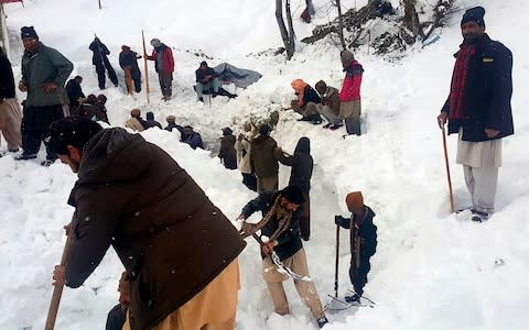 Local residents search for the avalanche victims in the snow in Neelum Valley, in Pakistan-administered Kashmir - Credit: AFP