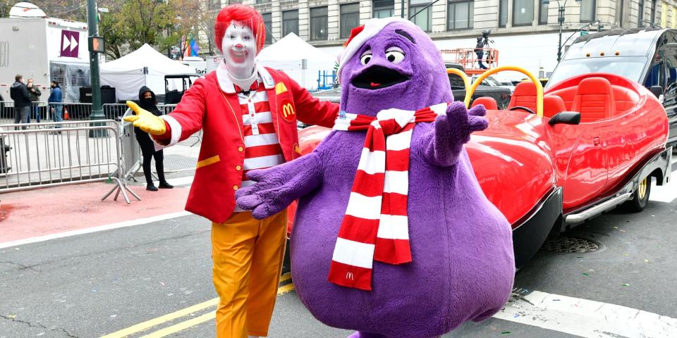 Ronald McDonald and Grimace with arms outstretched standing on street at Macy's parade