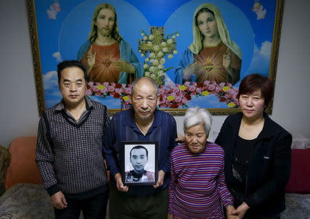 Jiang Weimao, 60, (L) and his wife Zhang Yinxiu, 53, (R), stand with Zhang's parents between them, as they pose with their dead son's picture at their house in Zhangjiakou, China, November 21, 2015. REUTERS/Kim Kyung-Hoon