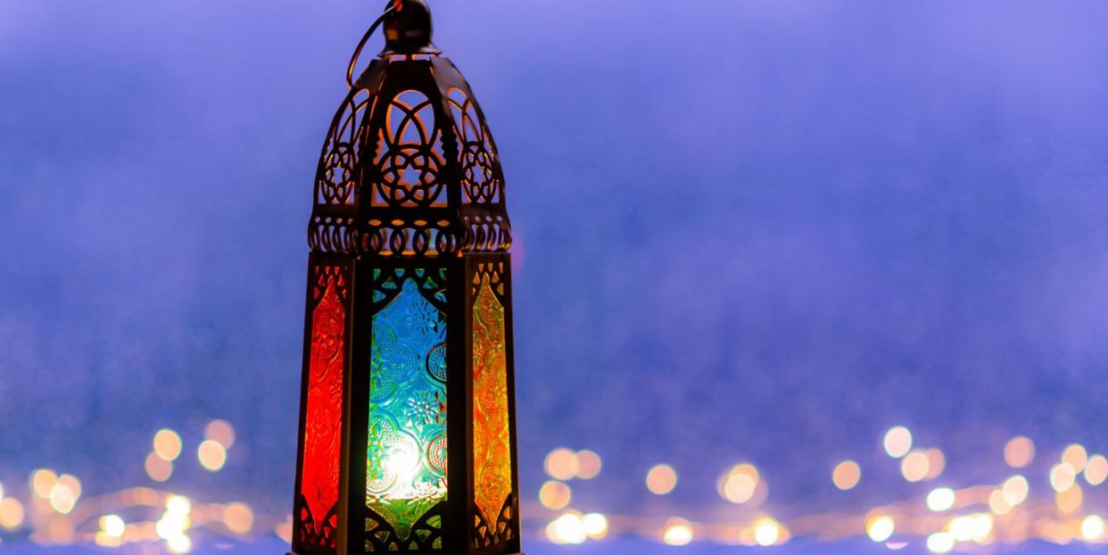 lantern with lights decorating for islamic new year put at window with blurred blue background