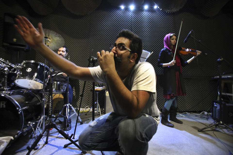 In this picture taken on Friday, Jan. 25, 2013, Iranian musician Danial Izadi performs with his harmonica in an unauthorized stage performance for his band called "Accolade" in Tehran, Iran. Heavy metal guitarists jamming in basements. Headphone-wearing disc jockeys mixing beats. Its an underground music scene that is flourishing in Iran, despite government restrictions. (AP Photo/Vahid Salemi)