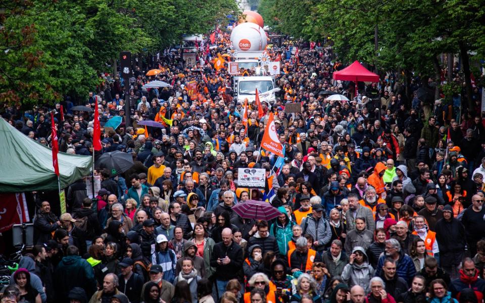 Demonstrators hold banners and flags as they protest on International Workers' day against the government's pension reform in Paris, France on May 1 - Ibrahim Ezzat/Anadolu Agency