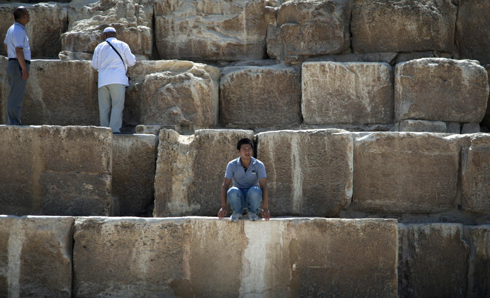 In this Thursday, Sept. 27, 2012 photo, a foreign tourist looks on as he sits during his visit to the historical site of the Giza Pyramids, near Cairo, Egypt. The Egyptian demonstrations against an online film that was produced by a U.S. citizen originally from Egypt and denigrates the Prophet Muhammad were part of a wider explosion of anger in Muslim countries. They happened near the U.S. Embassy, far from the pyramids of Giza on Cairo's outskirts, and a lot further from gated Red Sea resorts, cocoons for the beach-bound vacationer. Yet the online or TV images _ flames, barricades, whooping demonstrators _ are a killjoy for anyone planning a getaway, even though the protests have largely subsided. Tour guides in Egypt say tourist bookings are mostly holding, but they worry about a dropoff early next year, since people tend to plan several months ahead.(AP Photo/Khalil Hamra)