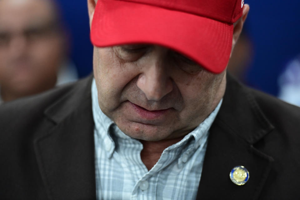 Doug Mastriano, in red baseball cap, bows his head.