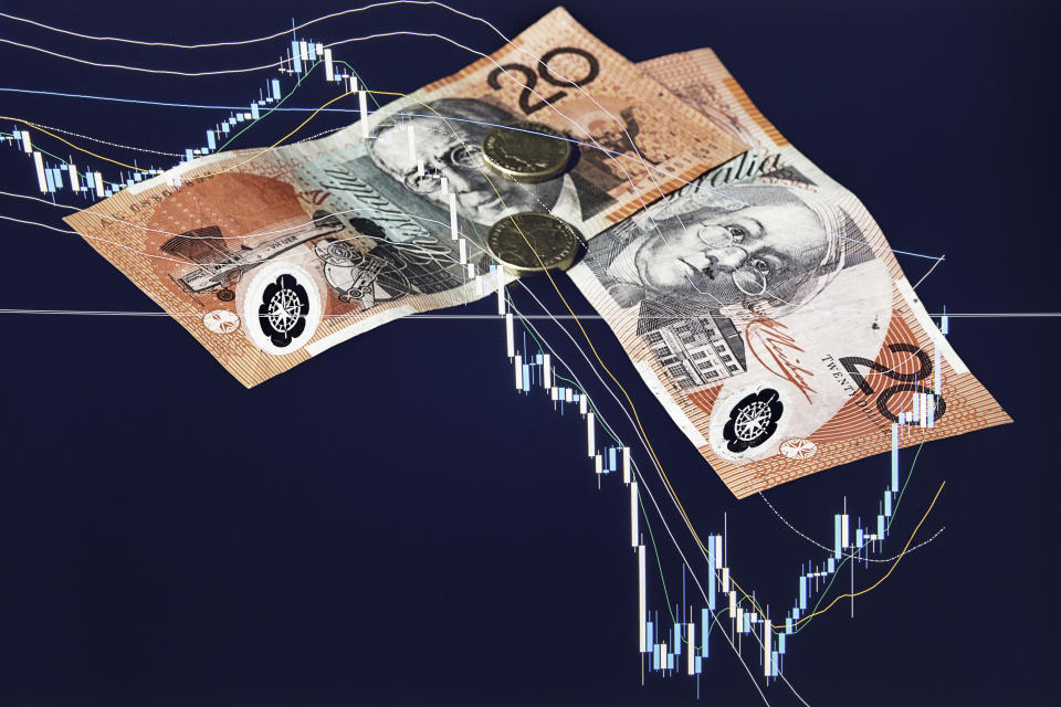 The financial market is having great impact over the markets around the world and the Australian Dollar. In this picture there is a chart of the stock market breakdown and two AUD banknotes and coins, due to the recession caused by Covid-19 flu