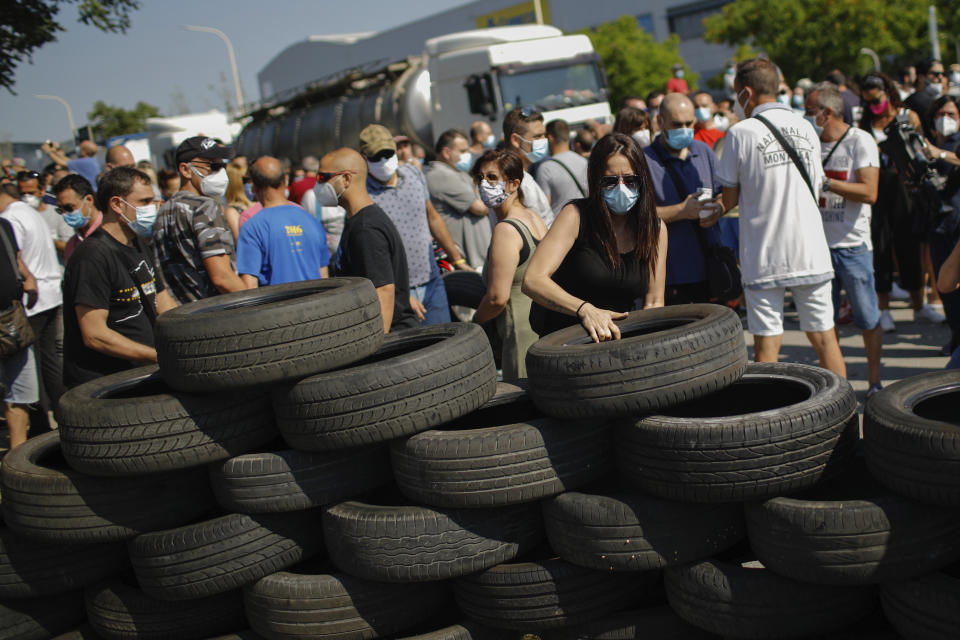 A woman makes a barricade off tyres during a protest by Nissan workers in Barcelona, Spain, Thursday, May 28, 2020. Japanese carmaker Nissan Motor Co. has decided to close its manufacturing plans in the northeastern Catalonia region, resulting in the loss of some 3,000 direct jobs. (AP Photo/Emilio Morenatti)