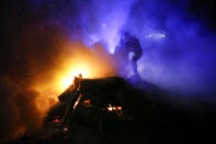 A protester, who planned to stop buses carrying passengers evacuated from the Chinese city of Wuhan, kindles a fire outside Novi Sarzhany, Ukraine, Thursday, Feb. 20, 2020. Several hundred residents in Ukraine's Poltava region protested to stop officials from quarantining the evacuees in their village because they feared becoming infected. Demonstrators put up road blocks and burned tires, while Ukrainian media reported that there were clashes with police, and more than 10 people were detained. (AP Photo/Efrem Lukatsky)