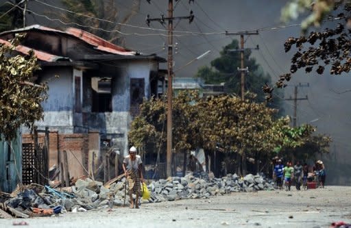 Muslim people walk past burnt houses as they evacuate to safer areas in Sittwe, capital of Myanmar's Rakhine state. Access to affected areas is restricted by the authorities, which say that the situation has been relatively calm in recent weeks