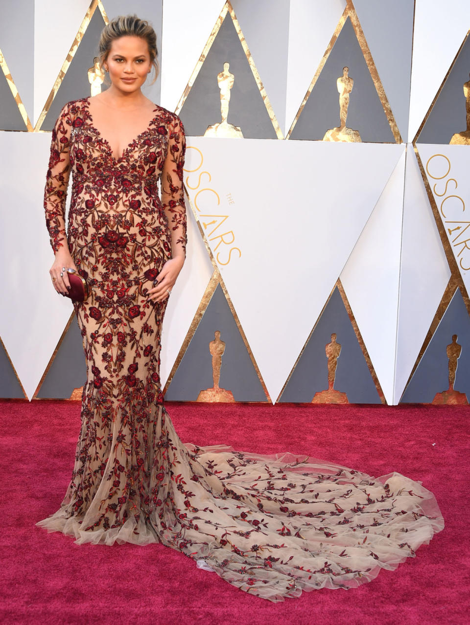 So trug Chrissy Teigen dieses transparente und mit rotem Floralmuster besticktes Abendkleid auf dem roten Teppich der Oscars 2016. (Bild-Copyright: Steve Granitz/WireImage)