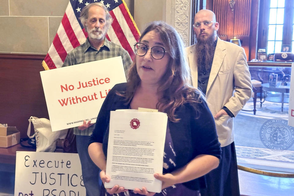 Elyse Max, co-director of Missourians to Abolish the Death Penalty, displays petitions asking Missouri Gov. Mike Parson to grant clemency to death row inmate David Hosier on Thursday, June 6, 2024, outside the governor’s office in the state Capitol, Jefferson City, Missouri. Behind Max, to the right, is the Rev. Jeff Hood, spiritual advisor for inmate David Hosier. The person to the left is not identified. (AP Photo/David Lieb)